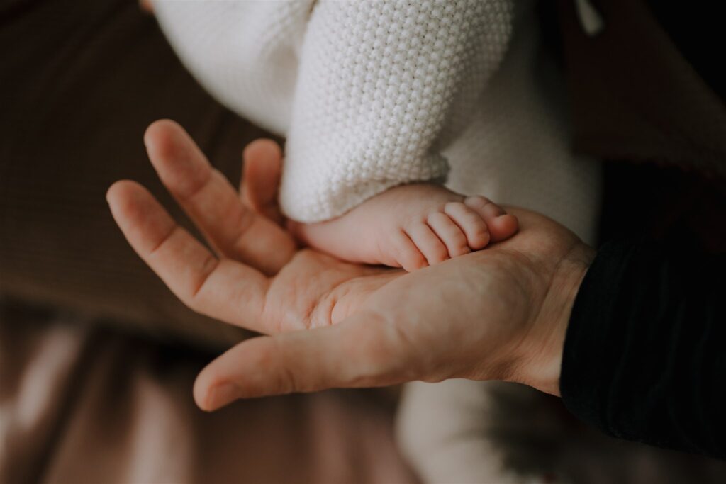 un petit pied de bebe dans la main de sa maman en séance photo avec un photographe a Bordeaux