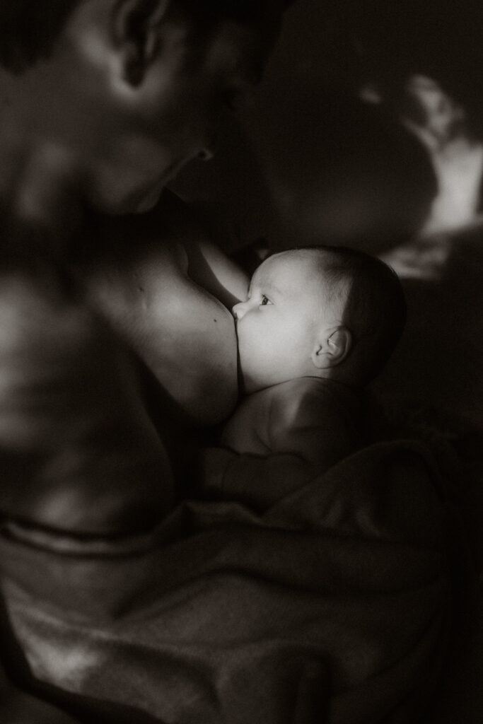 photo entour et blanc à fort contraste d'un bébé allaitant lors d'une séance photo à domicile à Bordeaux