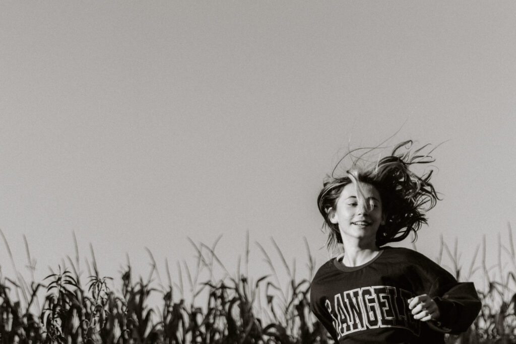 portrait en noir et blanc d'une jeune fille qui saute d'un trampoline les cheveux au vent