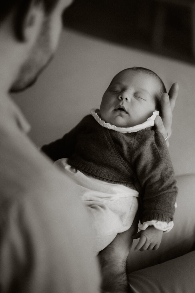 photo en noir et blanc d'un bébé dans les bras de son papa en séance photo avec un photographe à Bordeaux