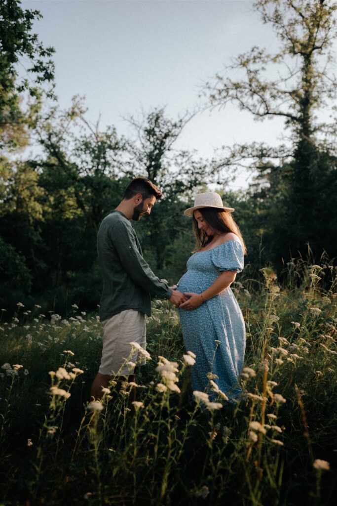 couple avec femme enceinte dans des fleurs champêtre lors d'une séance photo autour de bordeaux