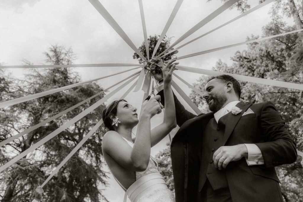 photo de mariage en noir et blanc - jeu du ruban bouquet de la mariée - domaine de la fauconnie en Dordogne - photographe mariage