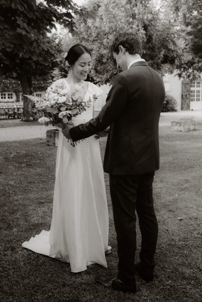 photo de mariés en noir et blanc se découvrant dans leur tenues de mariés pendant le first look au logis de la montagne vers Perigueux. Photographe mariage