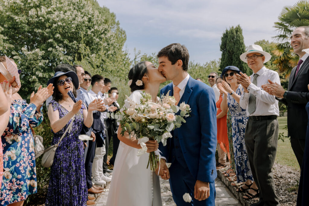 mariés s'embrassant dans l'allée avec les invités qui applaudissent à Perigueux - photographe mariage